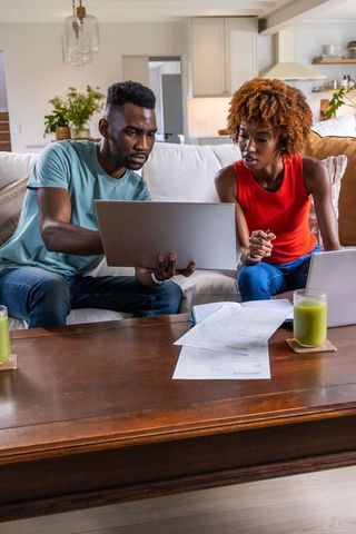 African american couple managing finances using laptop, reviewing bills and budgeting