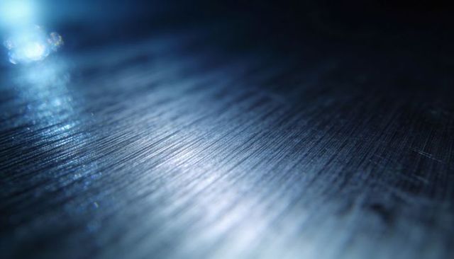 Brushed metal surface revealing diagonal grain and blue specular highlights