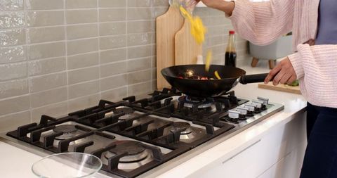 Woman Stir-Frying Vegetables in Modern Kitchen