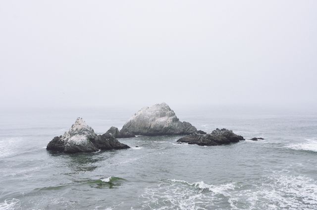 This image showcases rocky outcrops in a foggy ocean, enveloped by a mist with gentle waves lapping at the stones. Ideal for use in travel and nature magazines, serene background themes, or oceanic conservation materials. The calm and tranquil setting makes it useful in mindfulness or relaxation contexts.