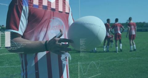 Teen rugby player holding ball with digital hud overlays on outdoor training field