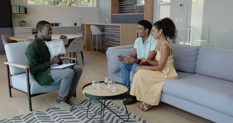 Man Consulting Couple in Modern Living Room Setting with Documents