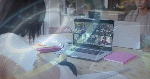 Teen studying at table with laptop joining virtual classroom and taking handwritten notes