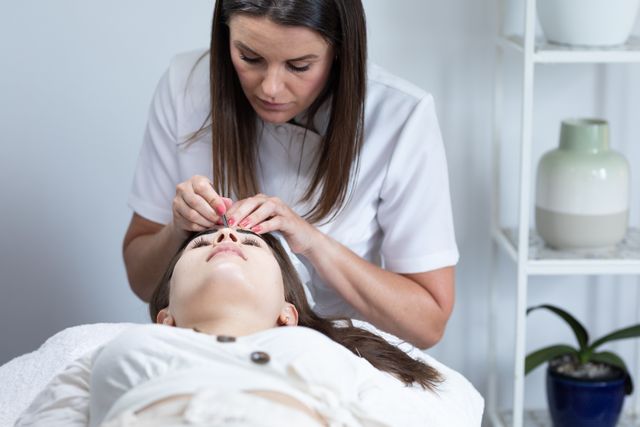 Female caucasian beautician dying eyebrows of a caucasian female customer. beauty treatment facial at beauty salon.