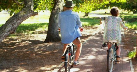 Couple Riding Bicycles Through Shaded Park Path - Download Free Stock Images Pikwizard.com