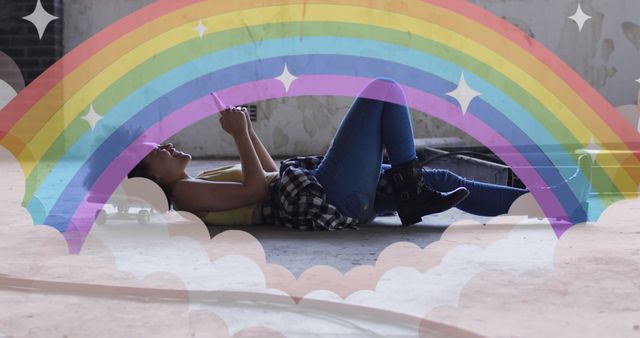 A young woman is lying on the floor, relaxed and looking at her smartphone, while a colorful illustrated rainbow with stars and clouds overlays the scene. Perfect for illustrating a carefree, dreamy lifestyle, creative projects, or promoting relaxation and digital recreation.