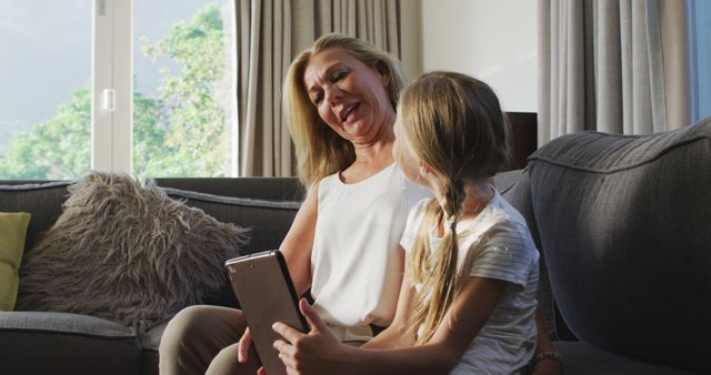 Grandmother and granddaughter bonding with tablet on sofa - Download Free Stock Images Pikwizard.com