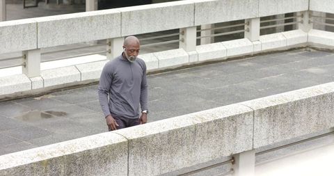 Senior African American Man Walking on Urban Elevated Walkway Wearing Earbuds and Watch