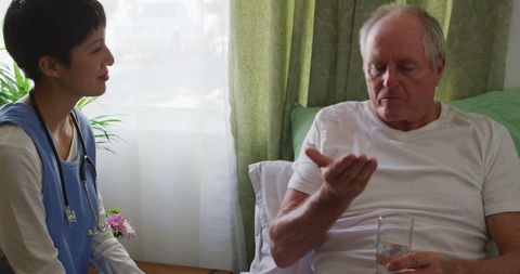 Senior Man Taking Medication with Doctor Assistance at Retirement Home