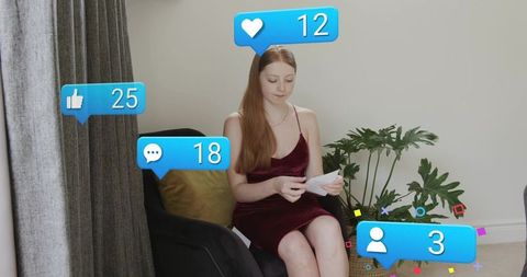 Young influencer sitting in velvet dress holding prints with floating media notifications