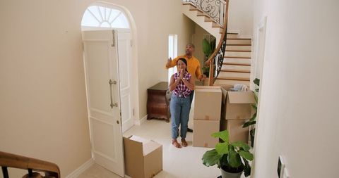 Couple unpacking in new home near staircase