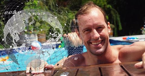 Smiling man leaning on pool edge while family plays in backyard with inflatables, summer