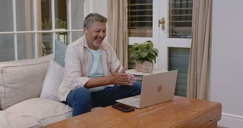 Senior Man Engaged in Video Call on Laptop at Home
