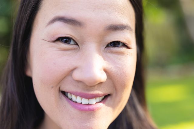 Close up portrait of happy asian woman standing in garden smiling, copy space. Domestic life, health, relaxation, inclusivity and lifestyle.