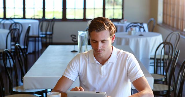 Young Man in White Polo Shirt Using Tablet in Casual Cafe - Download Free Stock Images Pikwizard.com