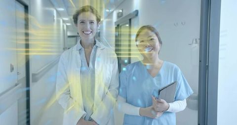 Smiling doctor and nurse using tablet in futuristic hospital corridor with digital beams
