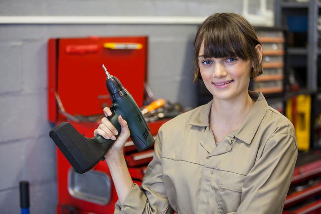 Female mechanic with pneumatic wrench at the repair garage