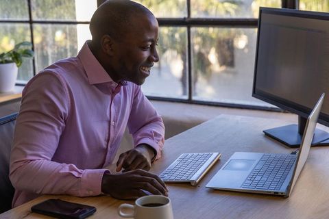 Professional Using Laptop at Office Desk in Modern Workspace