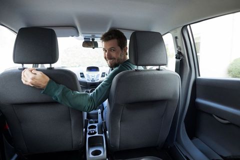 Man in green shirt turning around inside compact car