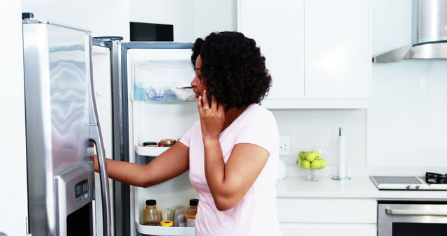 Woman Talking on Phone While Looking in Refrigerator at Home - Download Free Stock Images Pikwizard.com