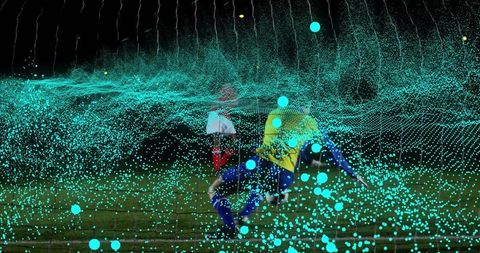 Sliding defender in yellow challenging forward under lights with teal particle overlay