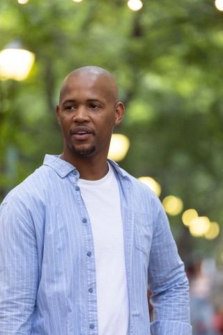 African american man standing on park walkway at dusk wearing blue shirt urban portrait