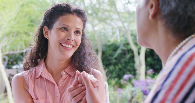 Happy biracial mother with adult daughter talking and holding hands in garden - Download Free Stock Photos Pikwizard.com
