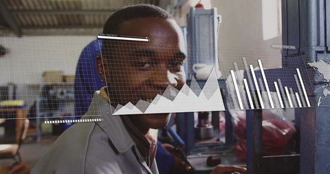 Smiling machine operator working at press with digital data overlay and industrial graphs