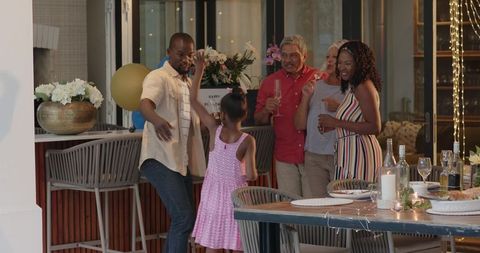 Multigenerational family celebrating on candlelit patio with dinner and floral centerpiece