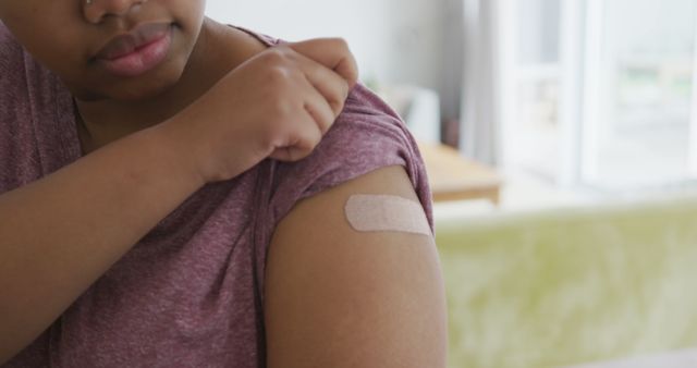 Happy african american woman with bandage on her arm after vaccination - Download Free Stock Photos Pikwizard.com