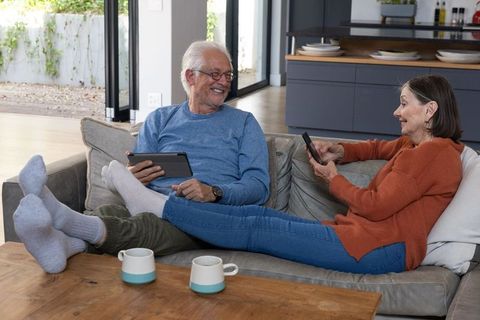 Senior couple relaxing with devices in modern living room