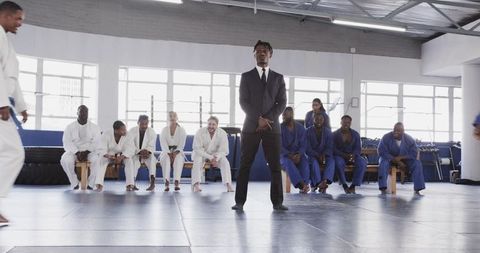 Martial arts instructor leading class with attentive students at gym