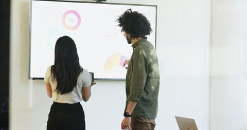 Coworkers analyzing data on digital screen in modern office