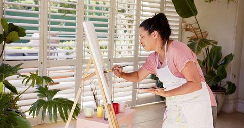 Woman creating art in bright creative home studio