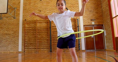 Child Enjoying Hula Hooping in School Gymnasium