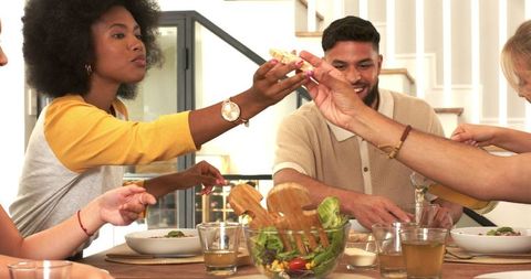 Diverse Friends Enjoying Meal Together, Passing Bread and Salad
