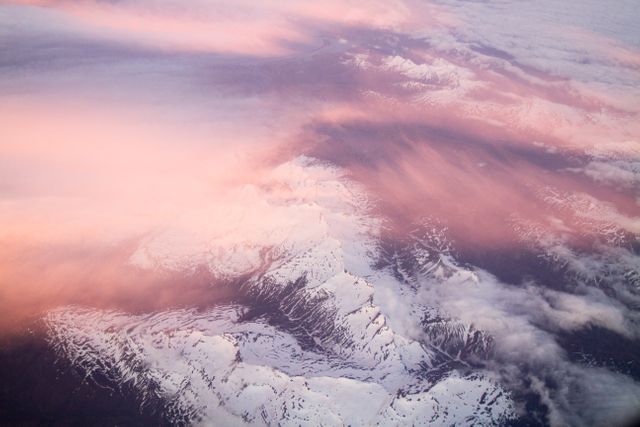 Aerial view of snowy mountain peaks with pink cloud cover at dusk - Download Free Stock Photos Pikwizard.com