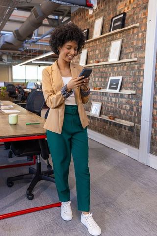 Professional Woman Walking with Smartphone in Modern Urban Office