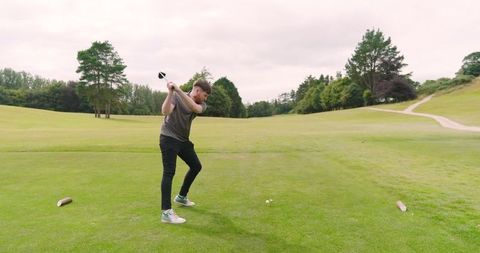 Golfer swinging club on well-maintained fairway