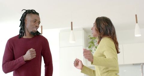 African American man and Indian woman sharing lively conversation in modern bright kitchen