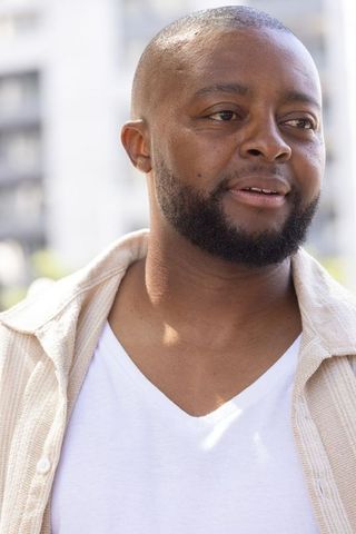 Confident african man gazing right wearing white v-neck shirt urban lifestyle portrait