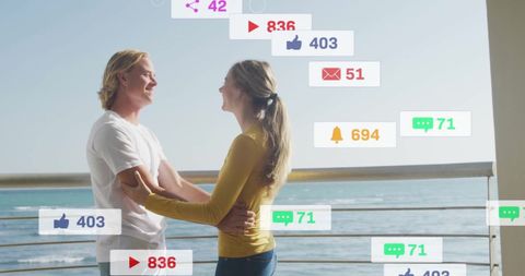 Romantic Couple Embracing with Social Media Notifications by Ocean