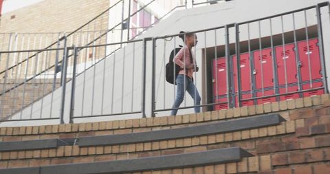 Child Walking on Campus By Red Lockers Wearing Backpack