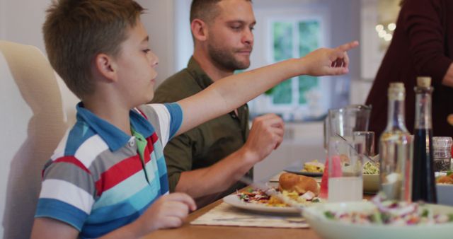 Family dinner with boy pointing and father eating - Download Free Stock Images Pikwizard.com