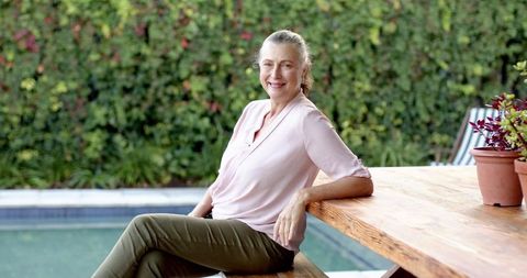 Senior woman relaxing by backyard pool with plants