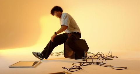 Trendy model on speaker box posing in modern studio