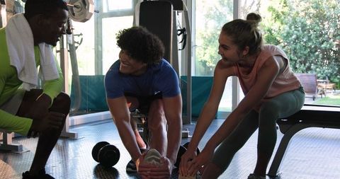 Couple Stretching in Gym with Personal Trainer for Flexibility and Workout Guidance