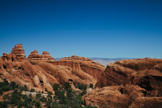 The image captures the beauty of red rock formations set against a clear blue sky. The rugged terrain adds to the sense of outdoor adventure and natural awe. Ideal for use in travel brochures, websites promoting outdoor activities, and nature photography portfolios.