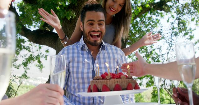 Happy friends celebrating mans birthday at outdoor restaurant