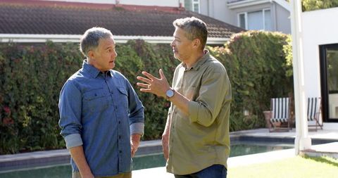 Senior male friends enjoying conversation outdoors by pool